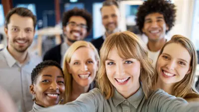 Eine bunt gemischte Gruppe von Mitarbeitern schaut lächelnd in die Kamera